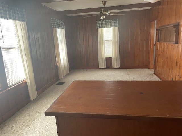 unfurnished room featuring beam ceiling, wood walls, and ceiling fan