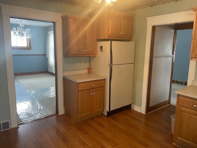 kitchen with dark wood-type flooring, white fridge, and a chandelier