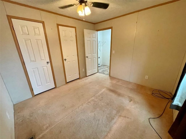 unfurnished bedroom with a textured ceiling, carpet floors, ceiling fan, and crown molding