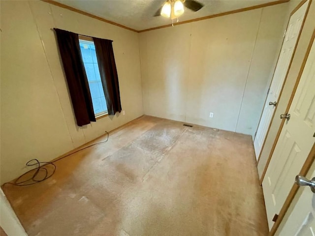 carpeted spare room with a textured ceiling, ceiling fan, and crown molding