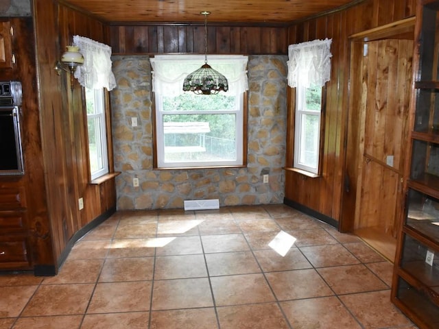 unfurnished dining area with light tile patterned flooring, wooden ceiling, wooden walls, and an inviting chandelier