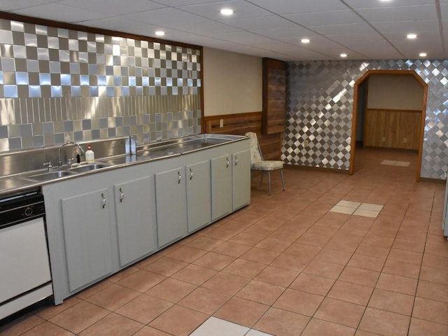 kitchen with stainless steel counters, dishwasher, light tile patterned flooring, and sink