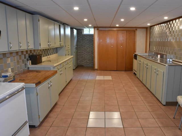 kitchen featuring sink, brick wall, decorative backsplash, light tile patterned floors, and range