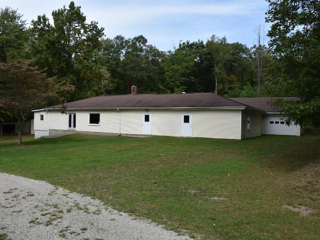 rear view of property featuring a lawn and a garage