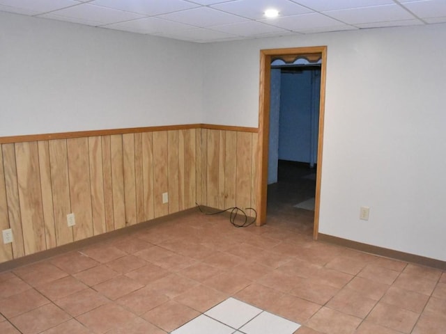 empty room with a paneled ceiling and wood walls