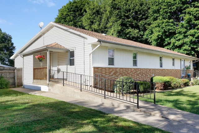 ranch-style house featuring brick siding, a front lawn, and fence