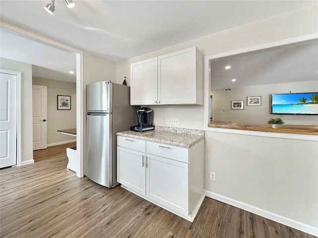 kitchen with light wood-type flooring, freestanding refrigerator, and white cabinetry