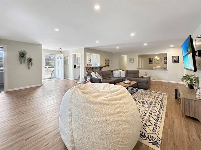 living room with baseboards, light wood-type flooring, and recessed lighting