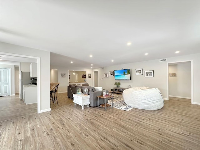 living room featuring baseboards, light wood-type flooring, and recessed lighting