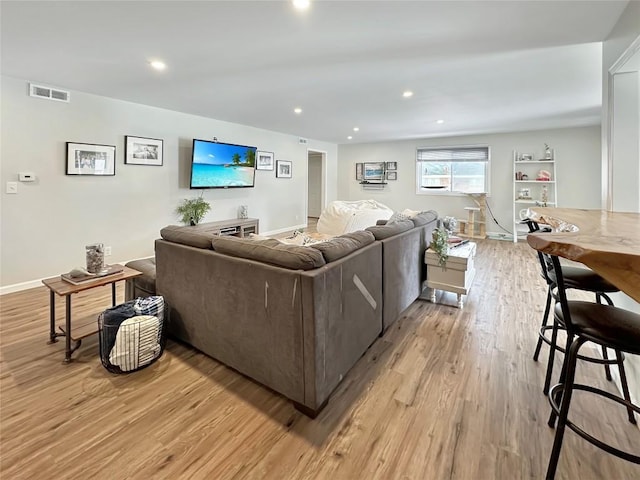 living area with light wood-style flooring, visible vents, baseboards, and recessed lighting