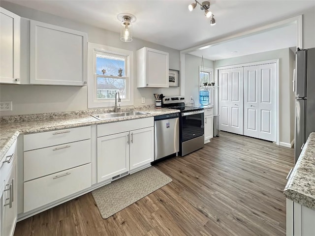 kitchen featuring stainless steel appliances, visible vents, white cabinetry, a sink, and light wood-type flooring