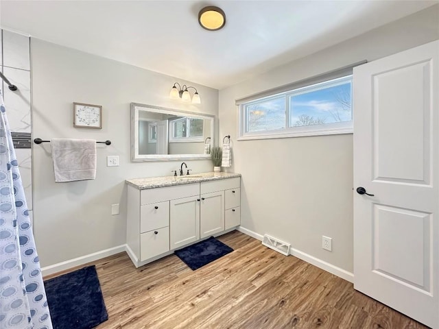 full bathroom with visible vents, vanity, baseboards, and wood finished floors