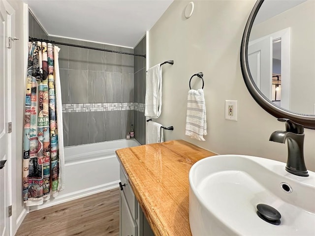 bathroom with shower / tub combo with curtain, a sink, and wood finished floors