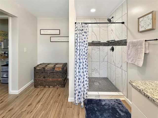 bathroom featuring a shower stall, baseboards, and wood finished floors