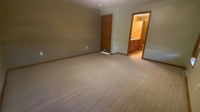 unfurnished bedroom featuring ensuite bath and light hardwood / wood-style flooring