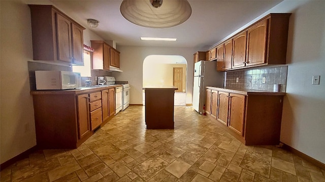 kitchen with white appliances, a center island, and backsplash