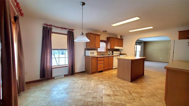 kitchen featuring white appliances, decorative light fixtures, and a center island