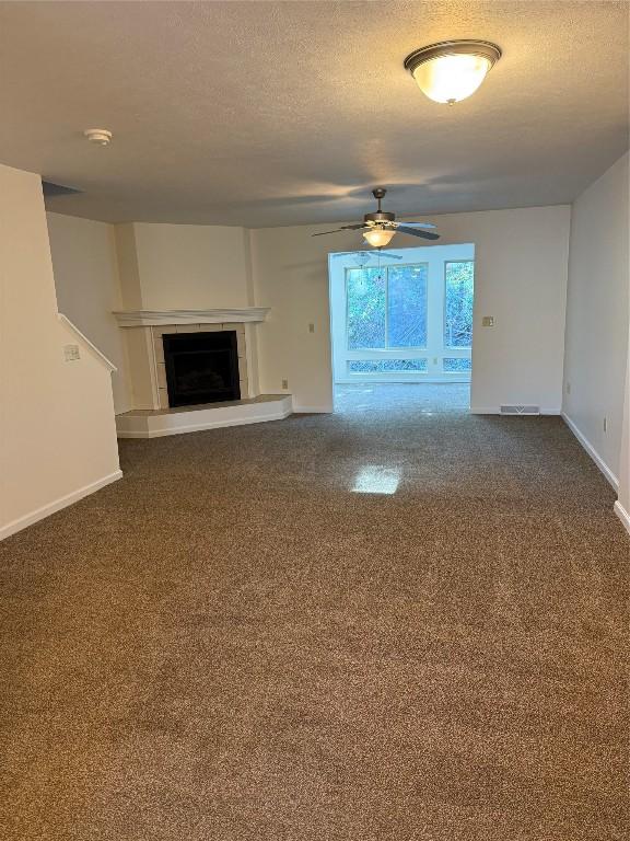 unfurnished living room featuring ceiling fan and a textured ceiling