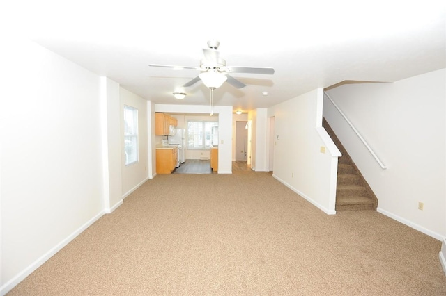 unfurnished living room featuring ceiling fan and light carpet