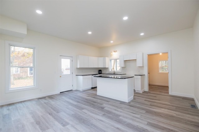 kitchen featuring white cabinets, a kitchen island, sink, and light hardwood / wood-style flooring