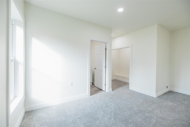 unfurnished bedroom with a closet and light colored carpet