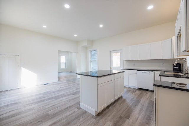 kitchen featuring white dishwasher, sink, light hardwood / wood-style floors, a kitchen island, and white cabinetry