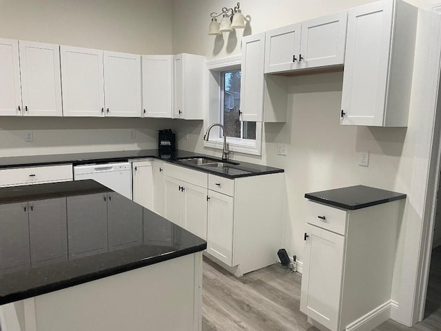 kitchen featuring dark stone counters, white dishwasher, white cabinets, sink, and light hardwood / wood-style floors