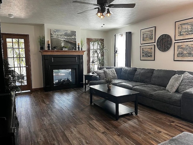 living room featuring a glass covered fireplace, wood finished floors, ceiling fan, and a textured ceiling