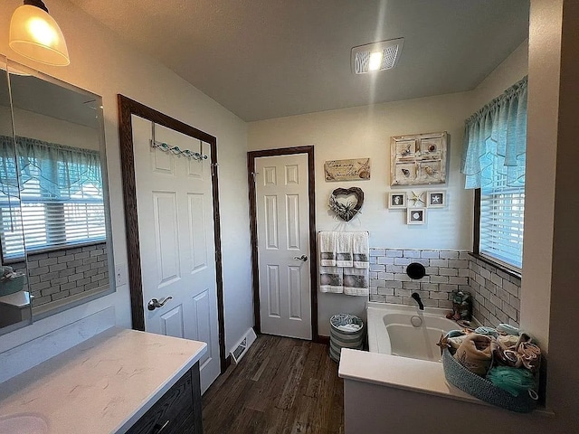 bathroom featuring visible vents, wood finished floors, a healthy amount of sunlight, and a garden tub