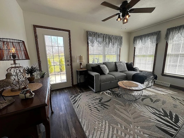 living area with a wealth of natural light, wood finished floors, ceiling fan, and baseboards