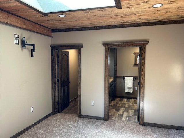 interior space featuring a skylight, dark carpet, and wood ceiling