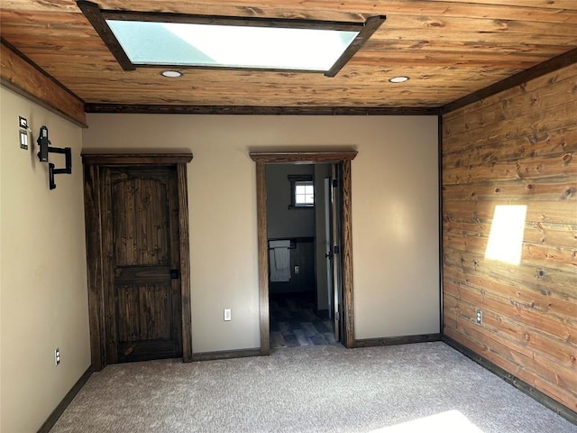 unfurnished bedroom with a skylight, dark carpet, wooden ceiling, and wood walls