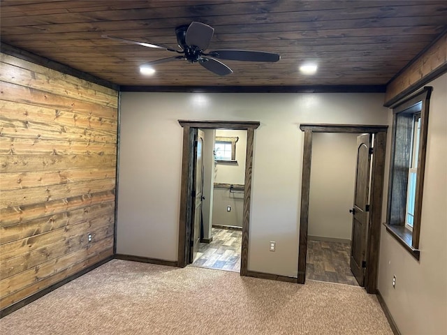 unfurnished bedroom featuring carpet flooring, ceiling fan, wood walls, and wood ceiling