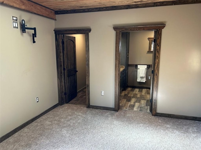 carpeted spare room featuring beamed ceiling and wood ceiling