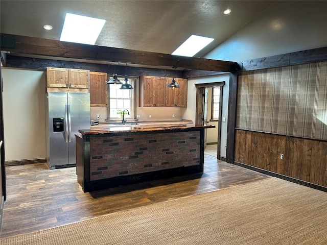 kitchen with wooden counters, sink, hanging light fixtures, stainless steel refrigerator with ice dispenser, and wood-type flooring