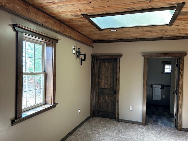 unfurnished bedroom with carpet flooring, a skylight, and wooden ceiling