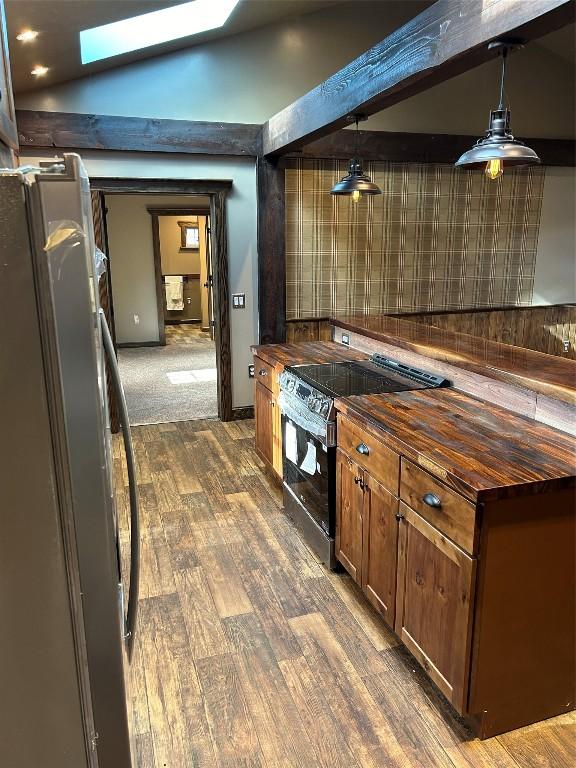 kitchen with lofted ceiling with skylight, wooden counters, electric range, fridge, and decorative light fixtures