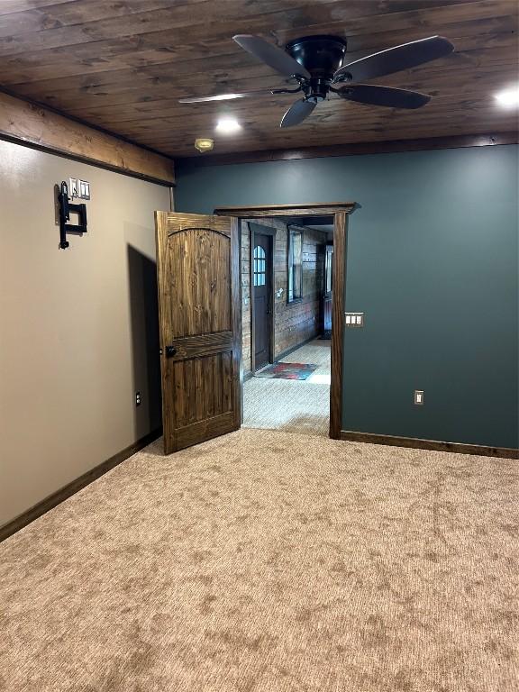 carpeted empty room featuring ceiling fan and wood ceiling