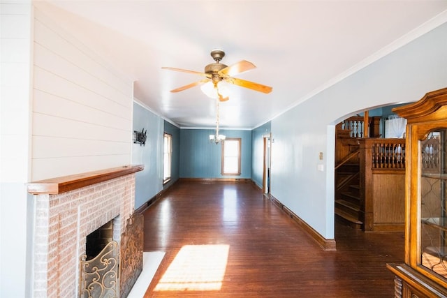 unfurnished living room with ornamental molding, a brick fireplace, ceiling fan with notable chandelier, and dark hardwood / wood-style flooring