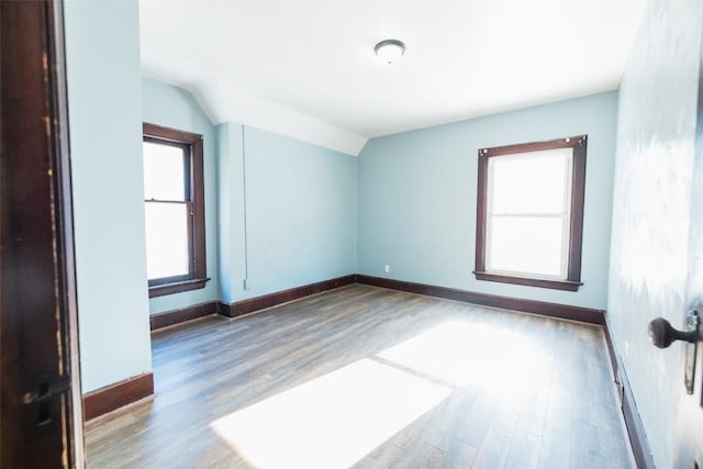 spare room with hardwood / wood-style flooring and vaulted ceiling