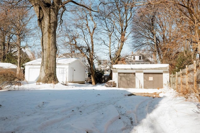 yard layered in snow featuring an outbuilding and a garage