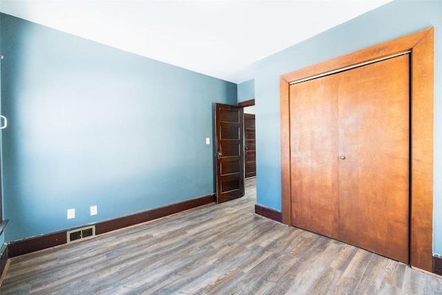 unfurnished bedroom featuring dark hardwood / wood-style floors and a closet