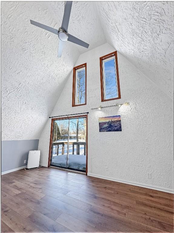 additional living space with ceiling fan, wood-type flooring, vaulted ceiling, and a textured ceiling