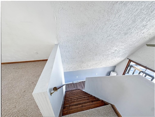 staircase with lofted ceiling and a textured ceiling