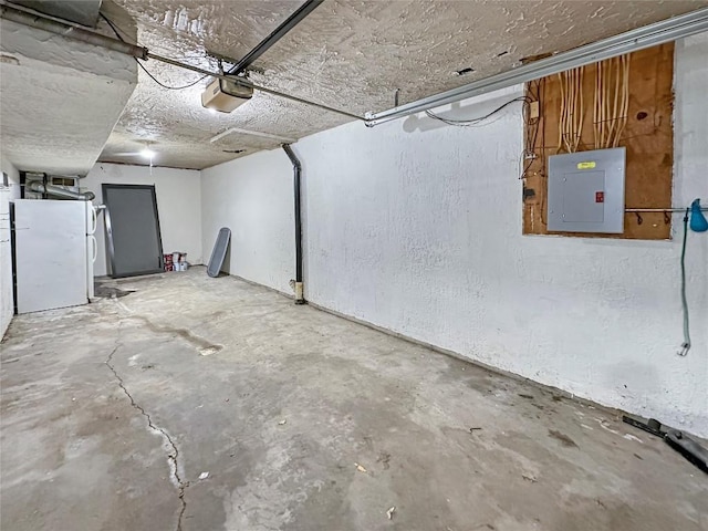 garage with a garage door opener, white fridge, and electric panel