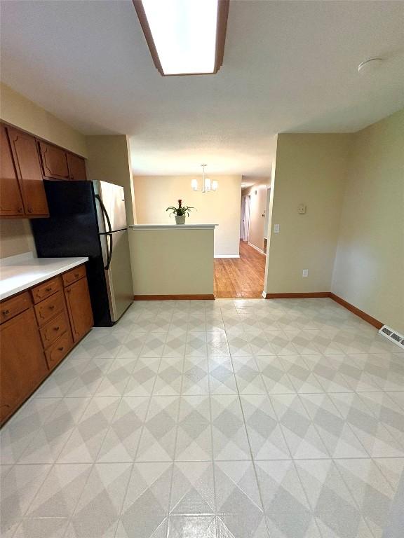 3322 Patio Dr, Millcreek, PA 16506 - kitchen with light floors, freestanding refrigerator, brown cabinets, light countertops, and baseboards