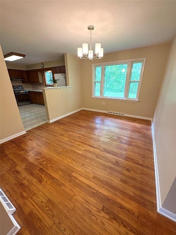 3322 Patio Dr, Millcreek, PA 16506 - unfurnished dining area with light wood finished floors, a chandelier, baseboards, and a textured ceiling