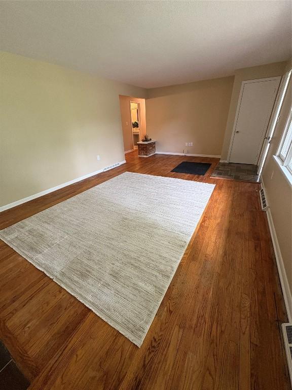 3322 Patio Dr, Millcreek, PA 16506 - unfurnished living room featuring dark wood-style flooring, baseboards, and an AC wall unit