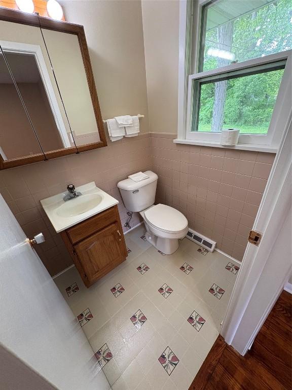 3322 Patio Dr, Millcreek, PA 16506 - bathroom featuring toilet, vanity, tile walls, and a wainscoted wall