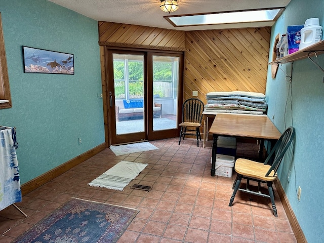 99 N Forest Ave, Meadville, PA 16335 - bedroom with a skylight, access to exterior, a textured wall, wooden walls, and a textured ceiling
